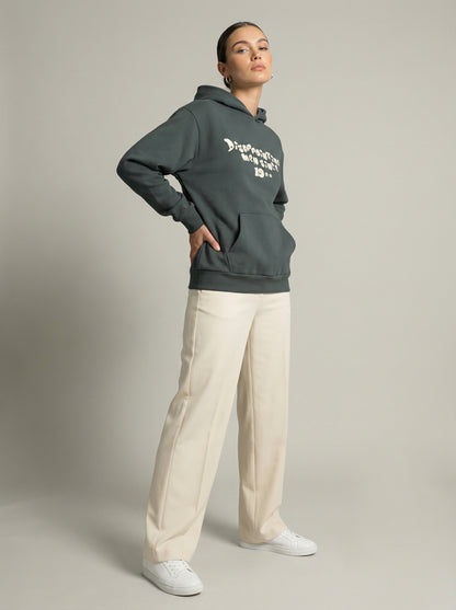 Person wearing a dark gray hoodie with text "Disappointing Men Since 19**" and light-colored pants on a neutral background